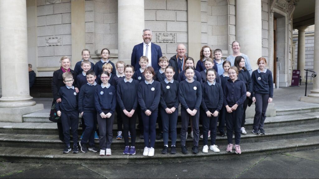 Photograph of Photo: St Anne’s NS Tyrrellspass, Westmeath 5th Class with Minister of State Christopher O’Sullivan, with Tóchar Stories Helen Shaw, ETHOS volunteer leader Eugene Dunbar and St Anne’s NS teacher Laura Lynch. Credit Stephen Crilly (Tóchar Stories).