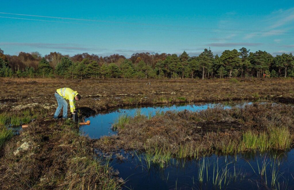 Photo of peat restoration contractor, Brian Gorman checking the recently installed weir on Clonbeale More Bog