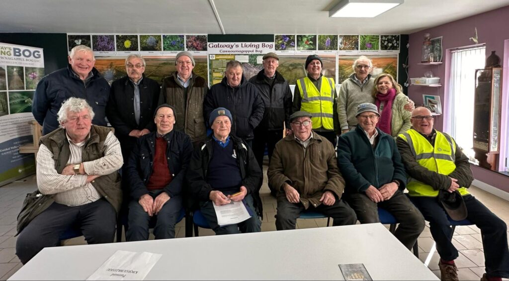 Photograph of Mountbellew Men’s Shed and Helen Shaw, Tóchar Stories at their first meeting in February 2025 with Gerry Rushe in white shirt in front row and Tom Kenny behind him.