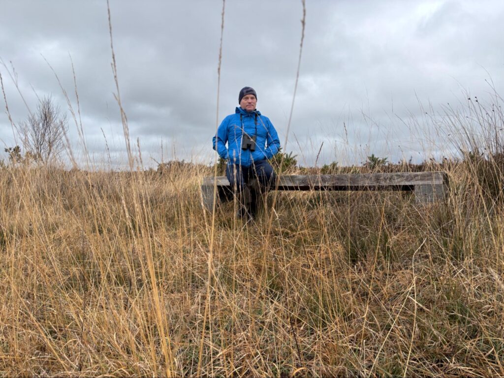 Photograph of Gearoid O’Foighil on Albert’s Bench in Scohaboy Bog put up by a local farmer who is known as the last  man to cut turf by hand on the bog 