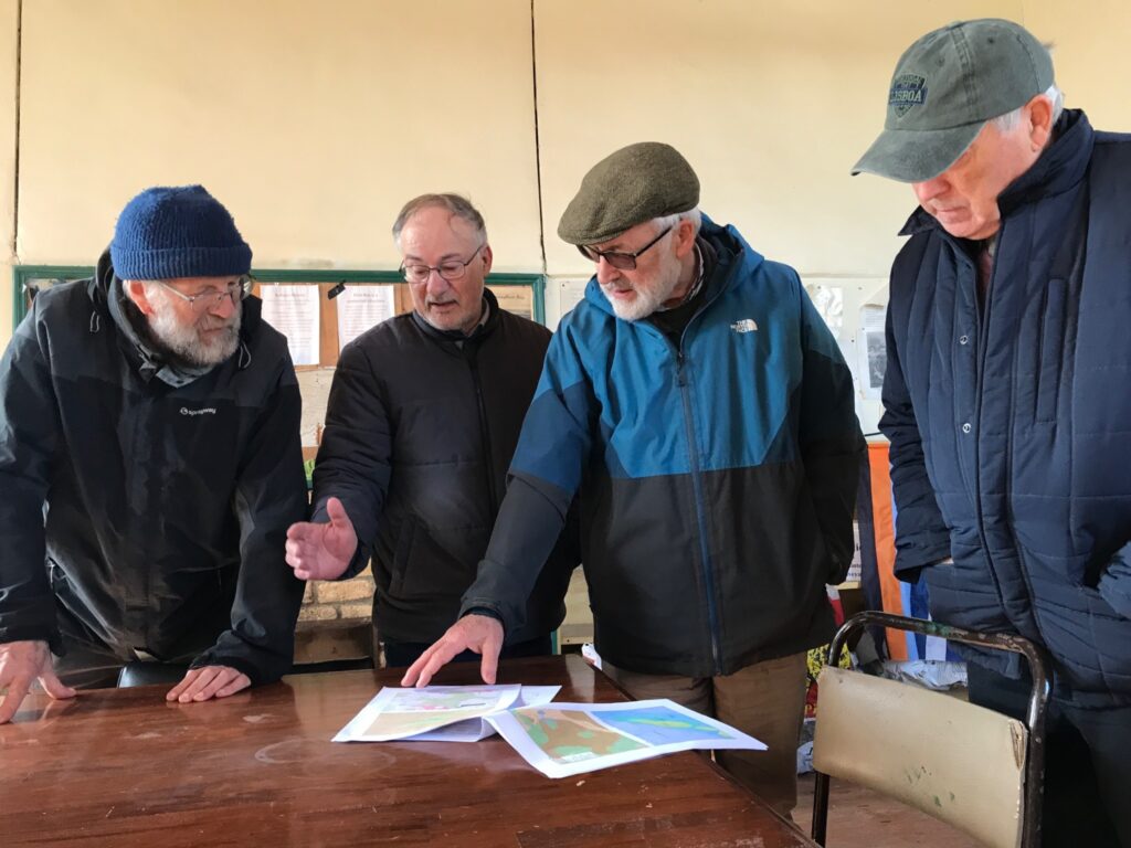 Photograph of Local historian Seamus Corcoran of the Lemanaghan Bog Heritage and Conservation Group showing the windfarm plan to a visiting group from the Community Wetlands Forum in April 2025 
