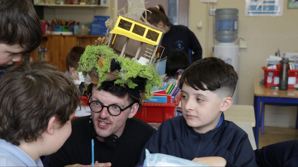 Photograph of  Performance Artist Luke Casserly in the classroom and with some of the pupils talking and imagining bog nature ( credit Stephen Crilly)