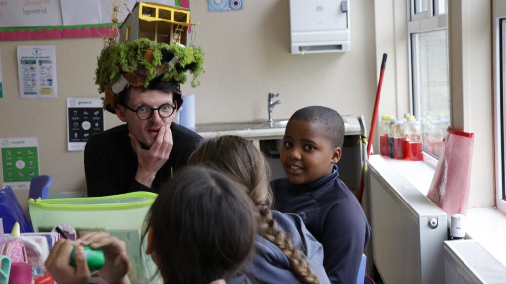 Photograph of Performance Artist Luke Casserly in the classroom and with some of the pupils talking and imagining bog nature ( credit Stephen Crilly)