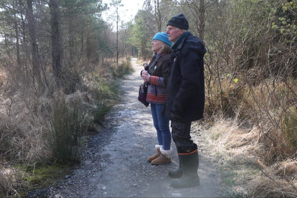 Photograph of Helen Shaw, Tóchar Stories with Hugh Shepherd, Abbeyleix Bog Project, on the loop walk in Abbeyleix Bog, Co Laois, March 2026 (Credit Stephen Crilly)