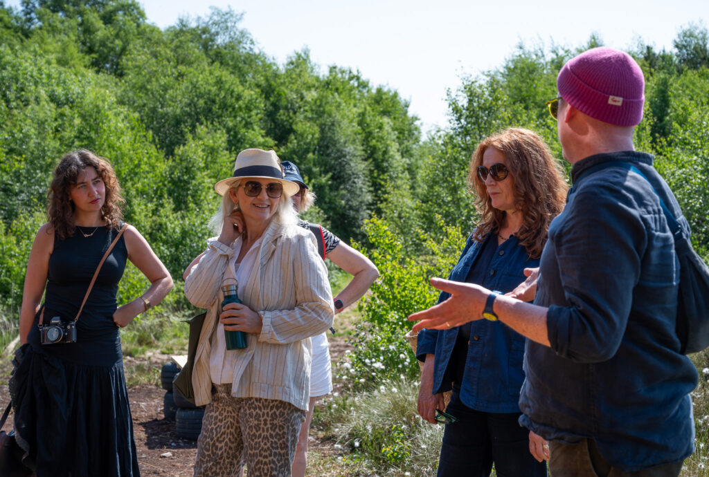 Group of four people standing on bog in sunshine chatting and smiling