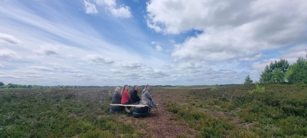 Landscape image of three people sitting looking out over Bog