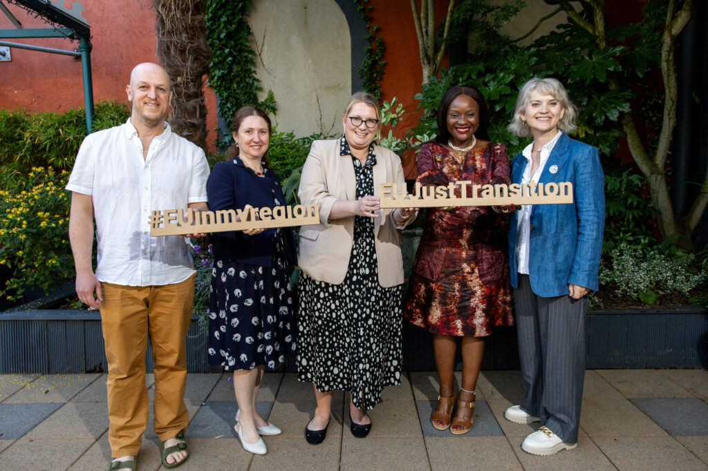 Five people standing together holding signs that says #EUinmyregion and #EUJustTransition
