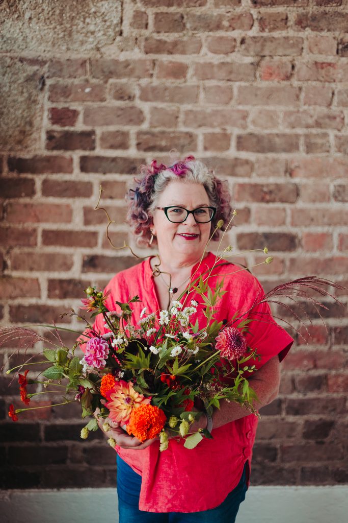 Woman standing smiling at camera and holding flowers