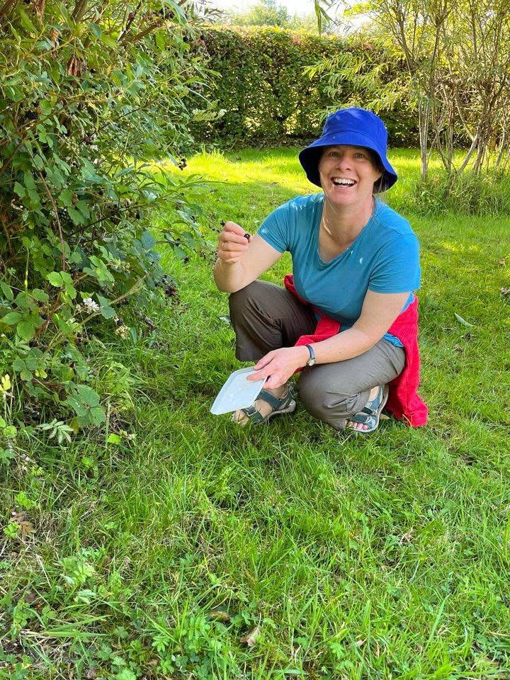 Woman crouching down by a shrub smiling and laughin
