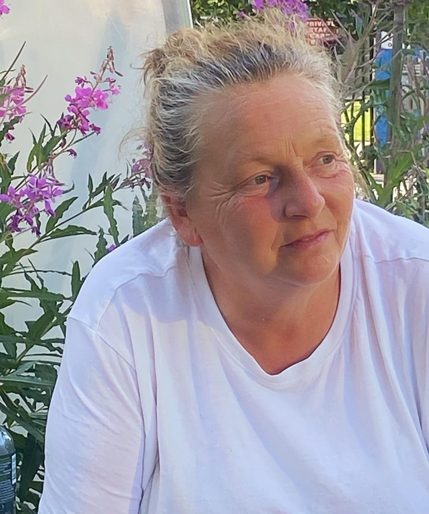 Woman sitting in front of flowers and looking out of frame