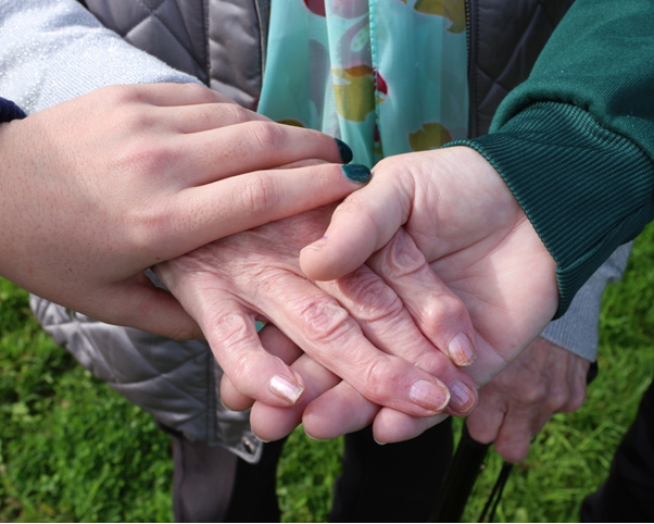 Three hands of women of different generations holding one another