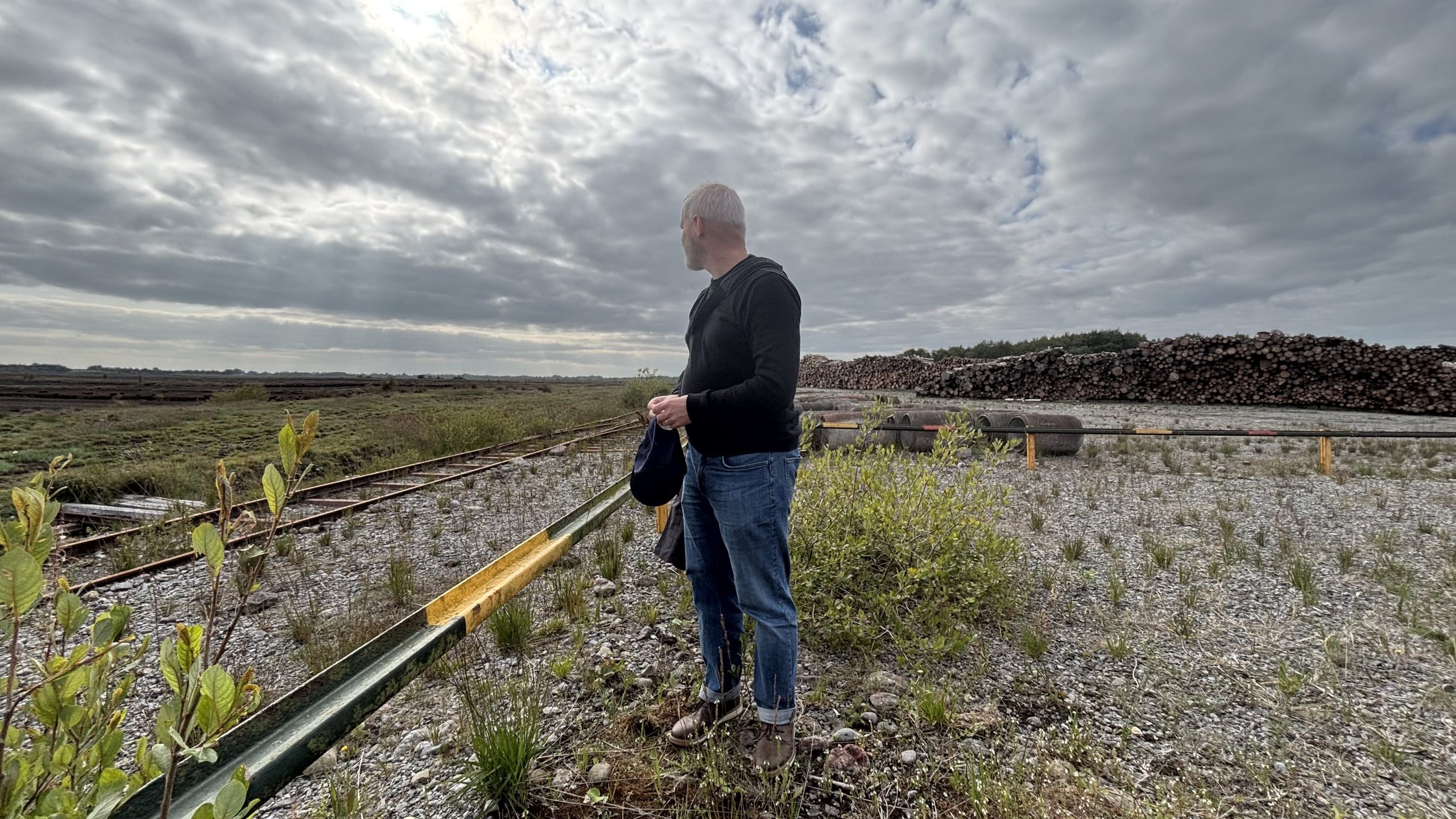 Photo: Archaeologist Dr. Michael Stanley at Toar Bog by the old Bord na Móna rail track with the felled logs and abandoned machinery behind him( Helen Shaw)